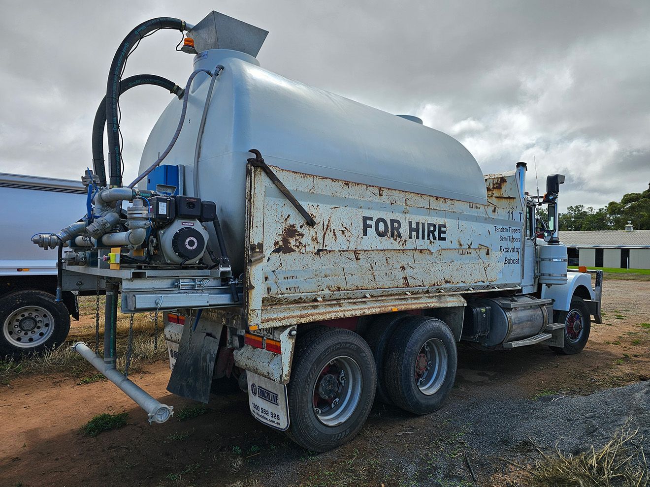 A for hire truck is parked in a gravel lot.