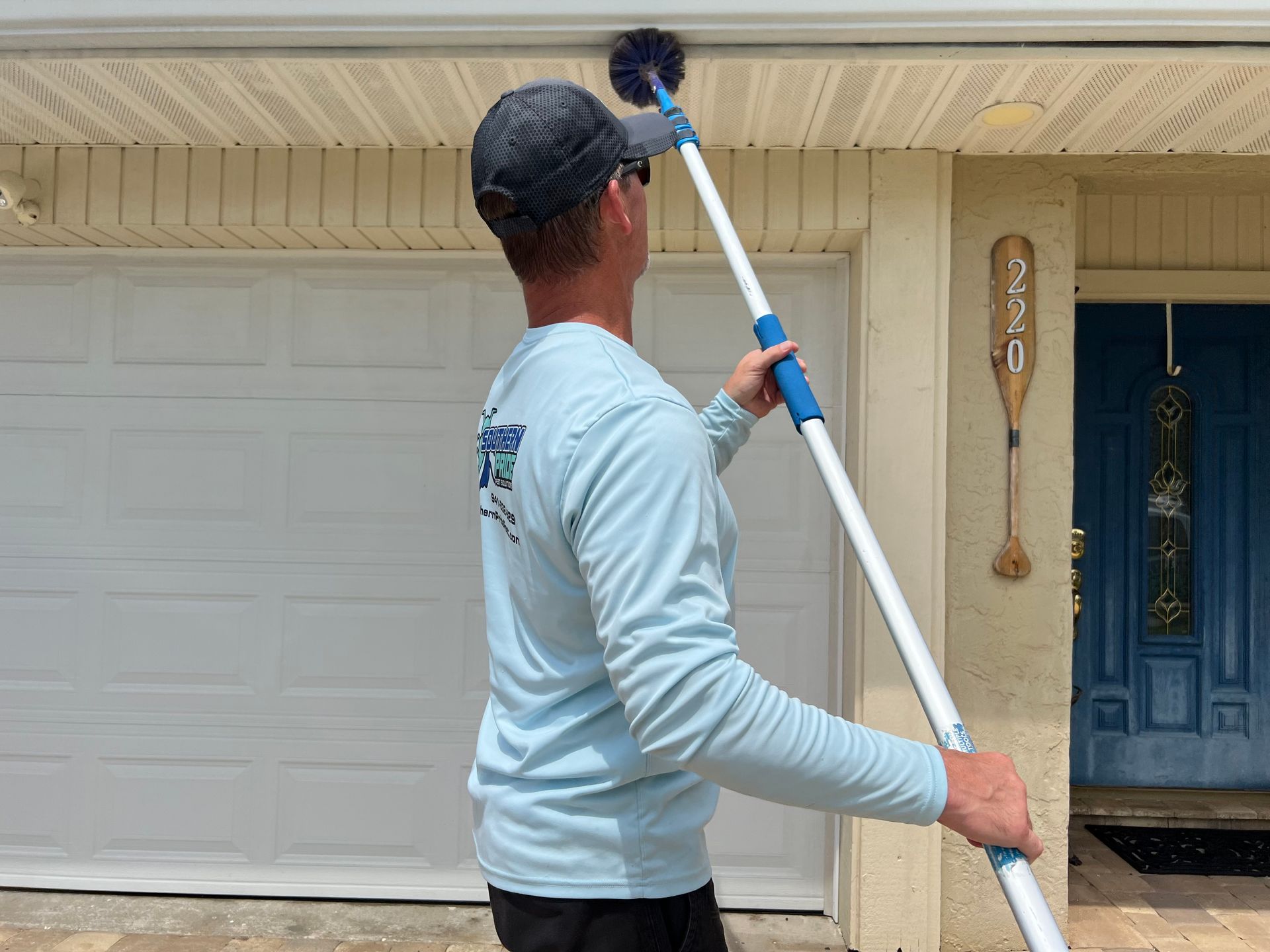 A man is cleaning the gutters of a house with a long pole.