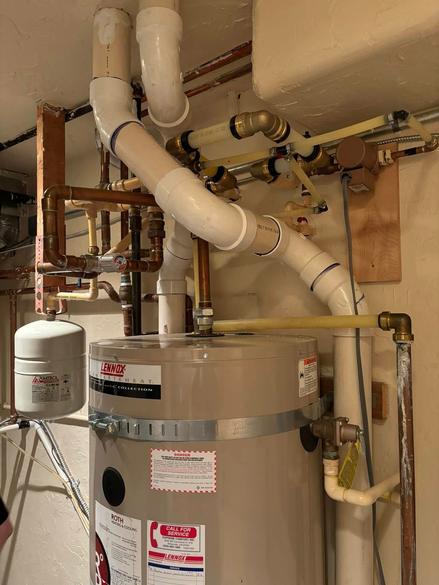 A water heater and its connected pipes, including a white vent pipe, copper plumbing, and an expansion tank.