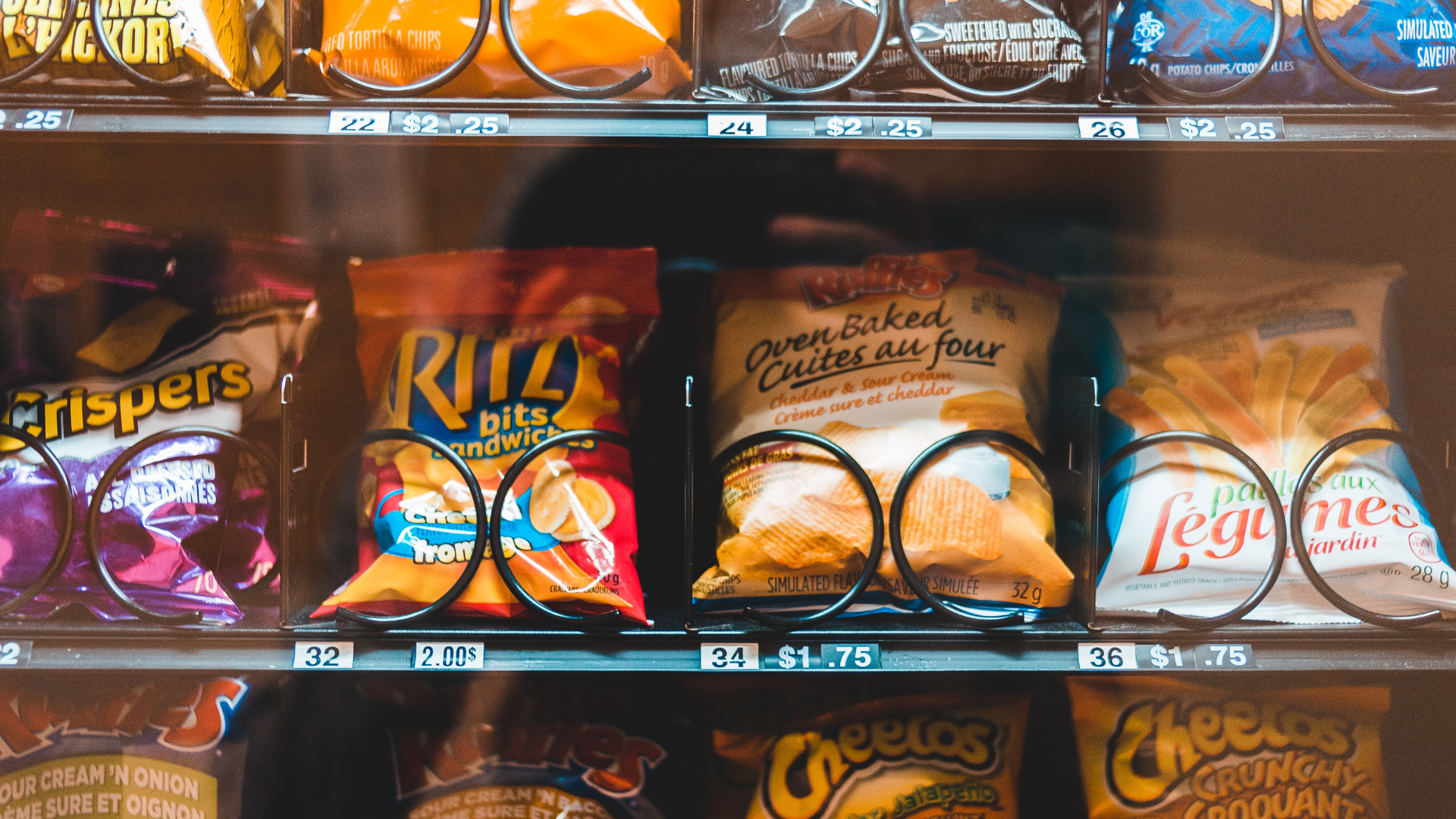 Vending machine with various snacks: chips, crackers, and crisps, with price tags visible.