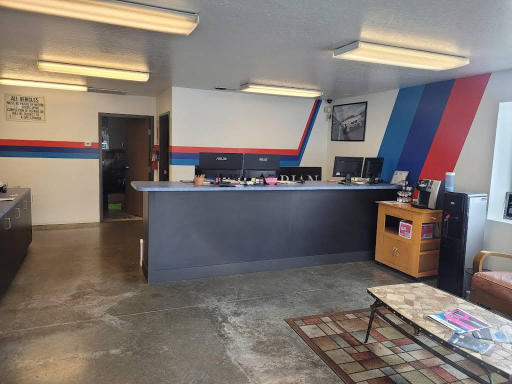 Interior of an auto repair shop with a reception desk, BMW logo wall, and waiting area. | Bavarian Auto Haus