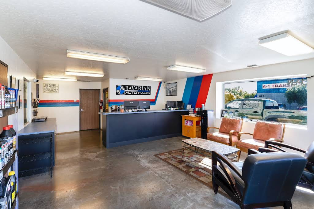 Reception area of an auto shop with chairs, desk, and counter with BMW logo on the wall. | Bavarian Auto Haus