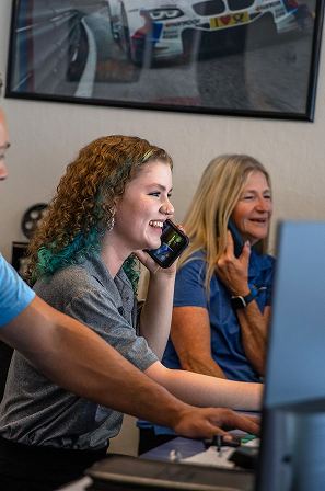 Two mechanics working on a car engine in a repair shop. One works on the engine while another watches. | Bavarian Auto Haus