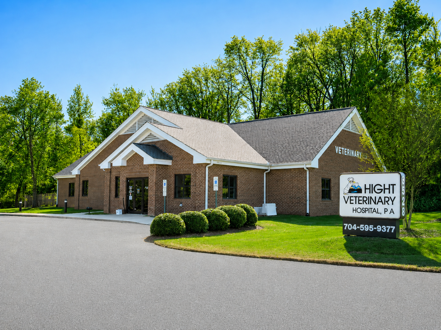Brick veterinary clinic with sign and green lawn beside a parking lot