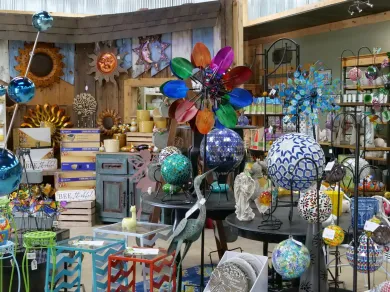 A gift shop display filled with colorful metal garden spinners, glass gazing globes, and decorative outdoor ornaments.