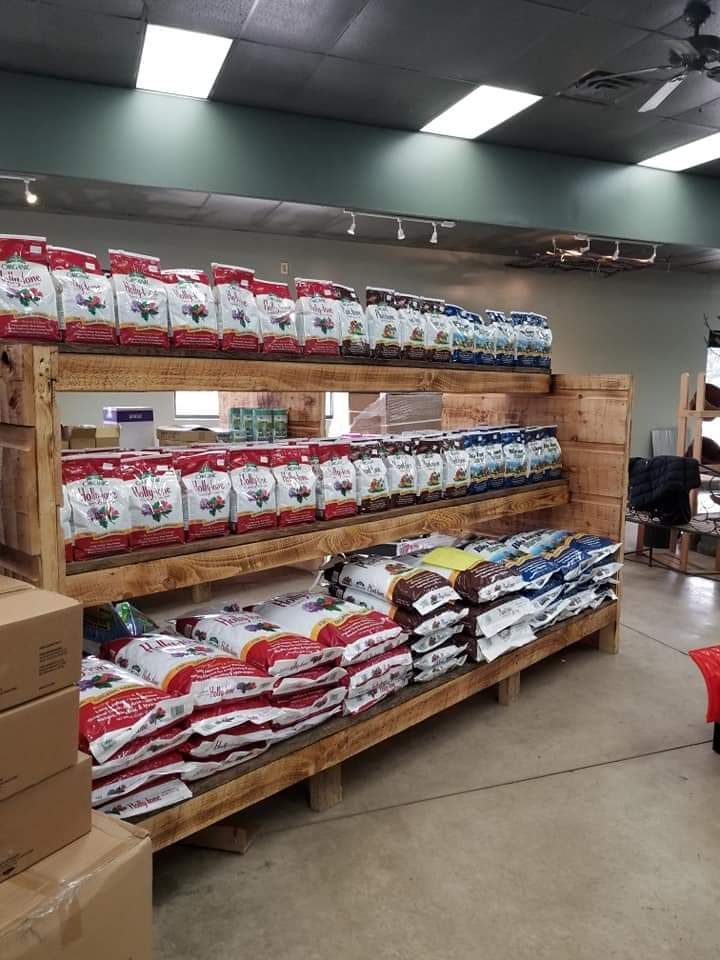 Warehouse aisle with stacked pet food bags on wooden shelves and pallets under fluorescent lights