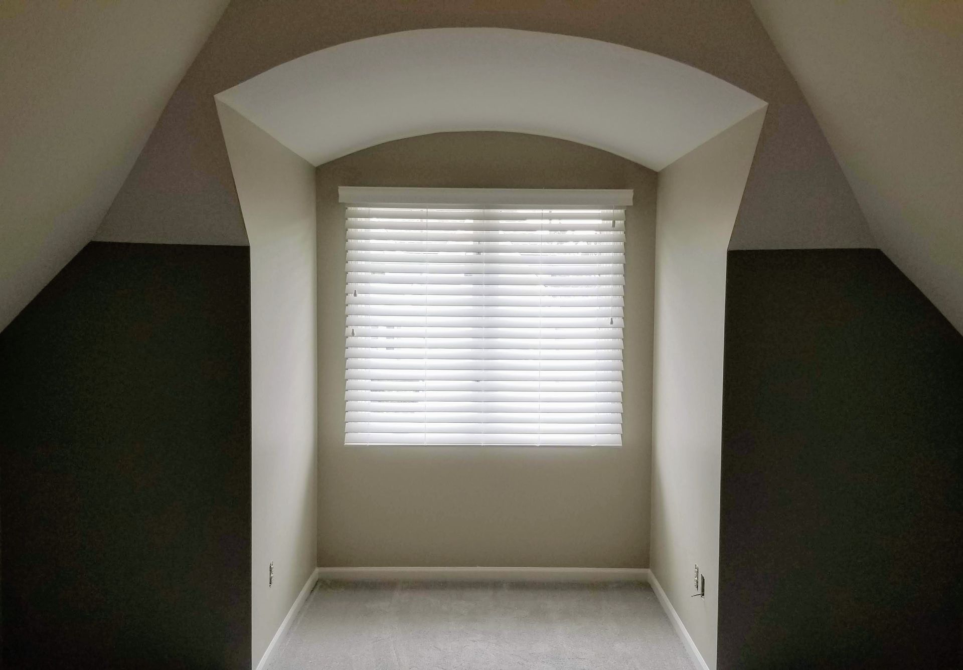An empty room with a window and blinds on it.