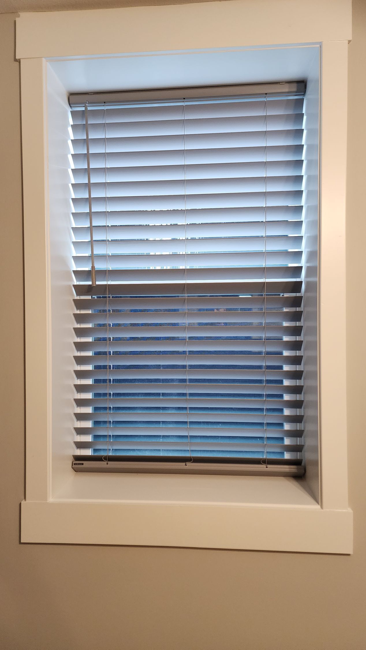 A window with blinds on it and a white frame