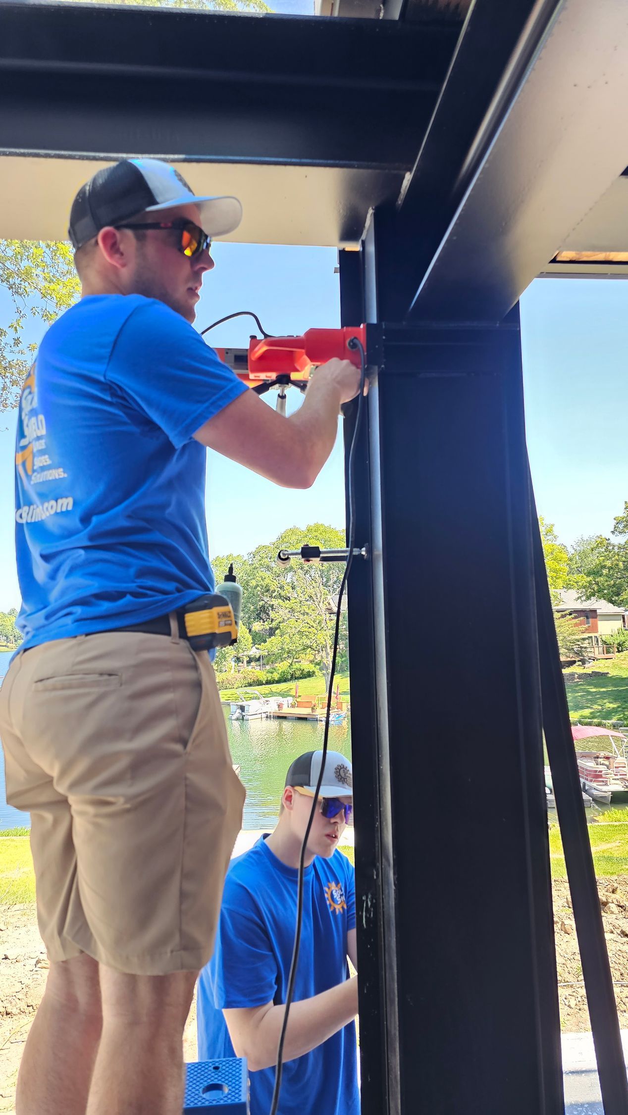 Solar Shield installer drilling into steel beam working on exterior patio shades