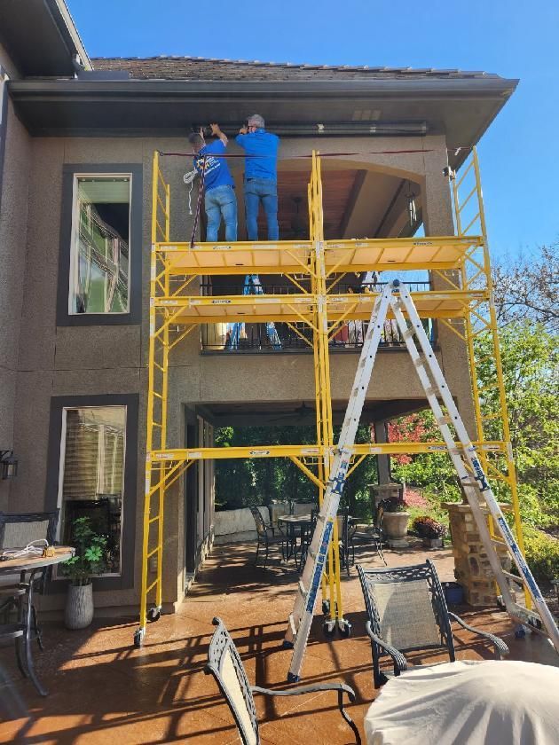 Solar Shield installers working on exterior patio shades on top of scaffolding