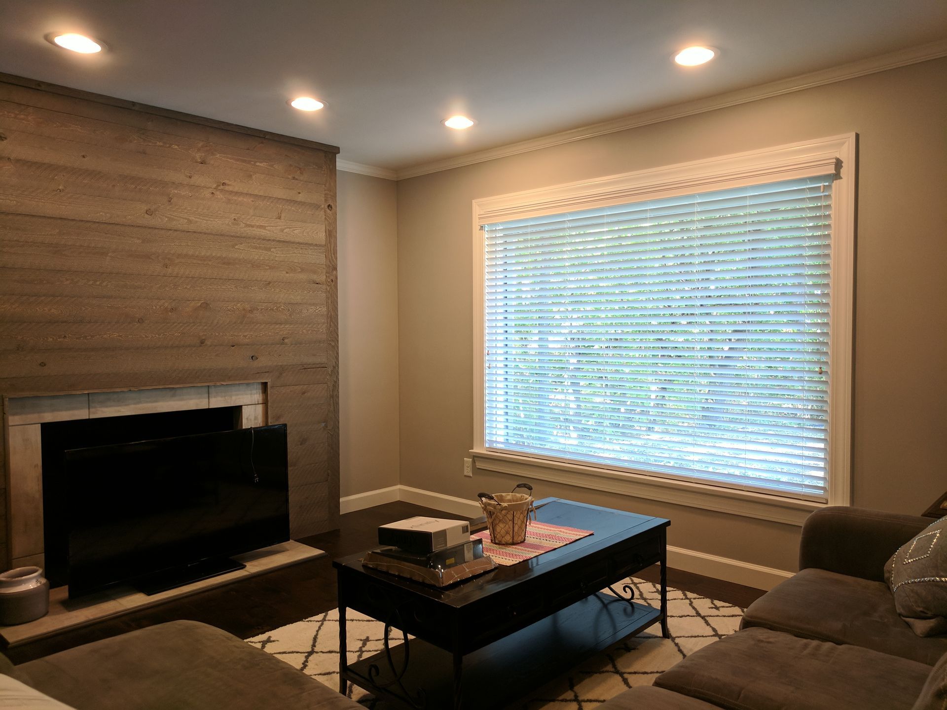 A living room with a fireplace , couch , coffee table and window.