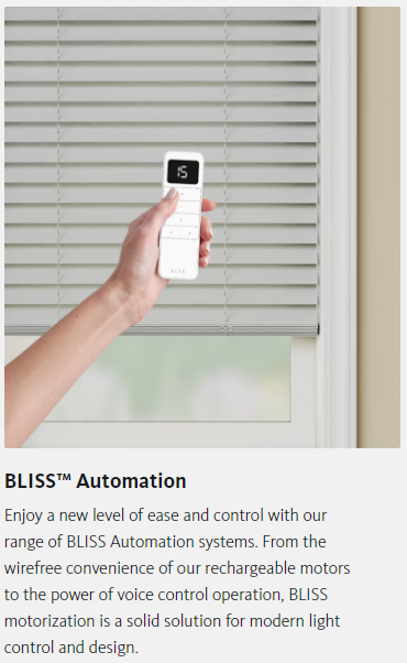A person is holding a remote control over a window blind.