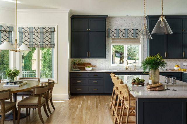 A kitchen with blue cabinets , a large island , a table and chairs.