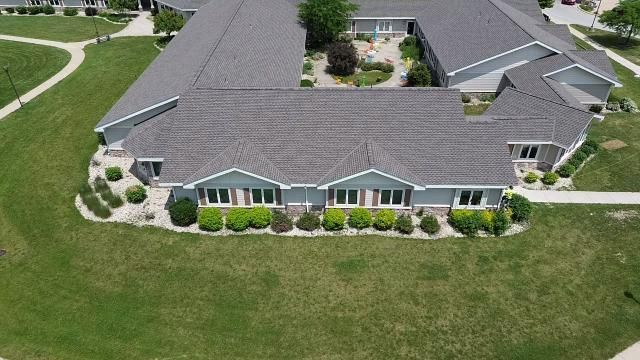 An aerial view of a gray-roofed building complex with surrounding green lawns and landscaped shrubbery.