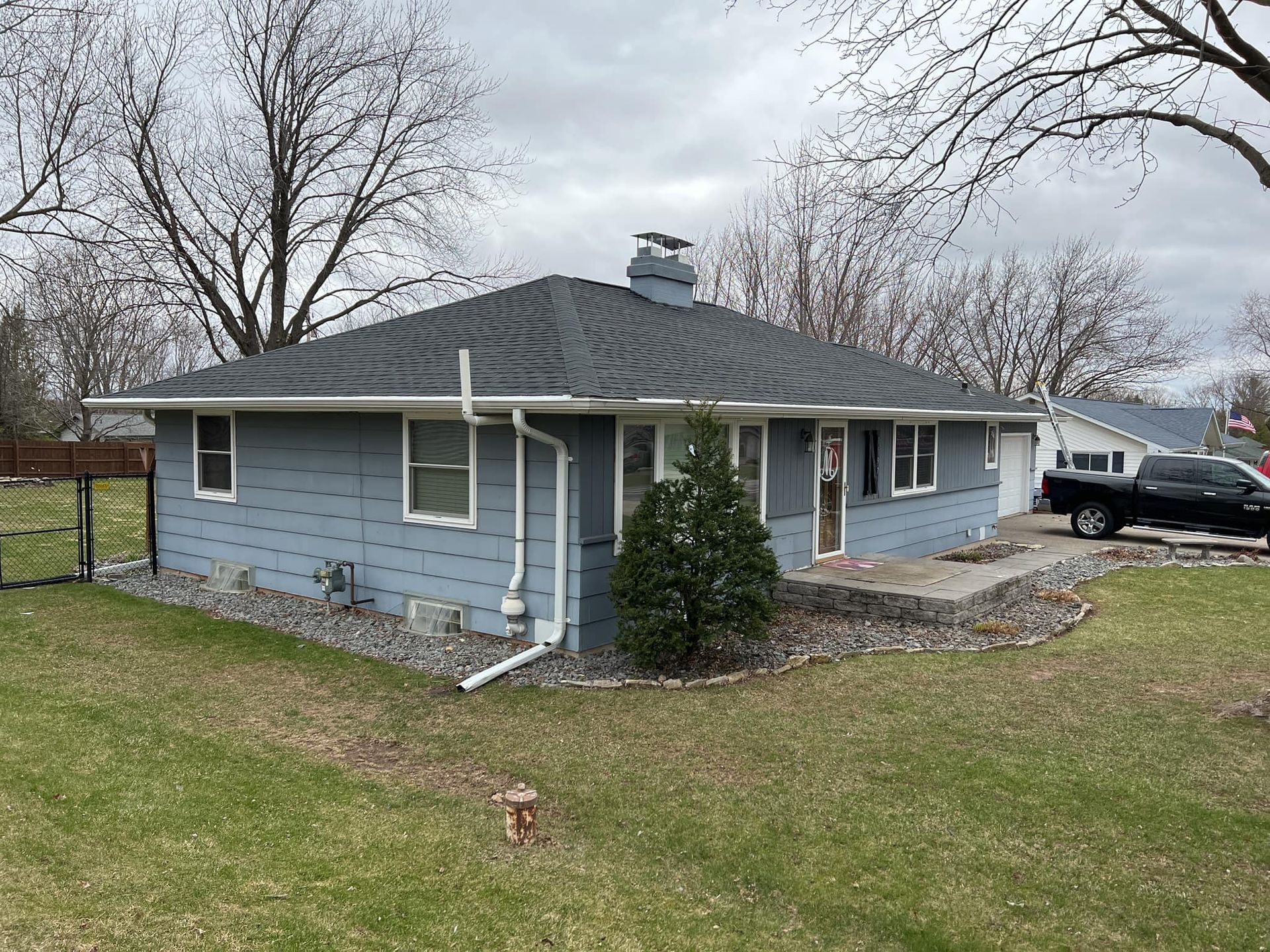 A blue house with a black truck parked in front of it.
