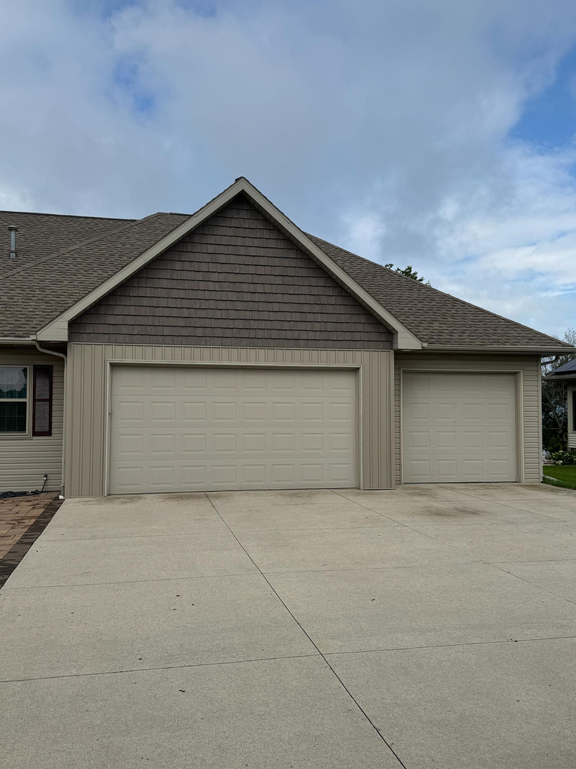A white house with a black roof is sitting on top of a lush green field.