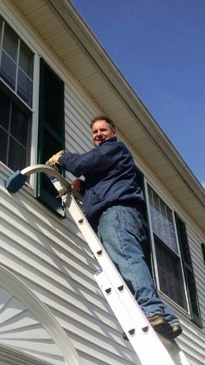 Owner Cleaning Window On A Ladder House — Hadley, MA — Family Window Cleaning & Property Maintenance