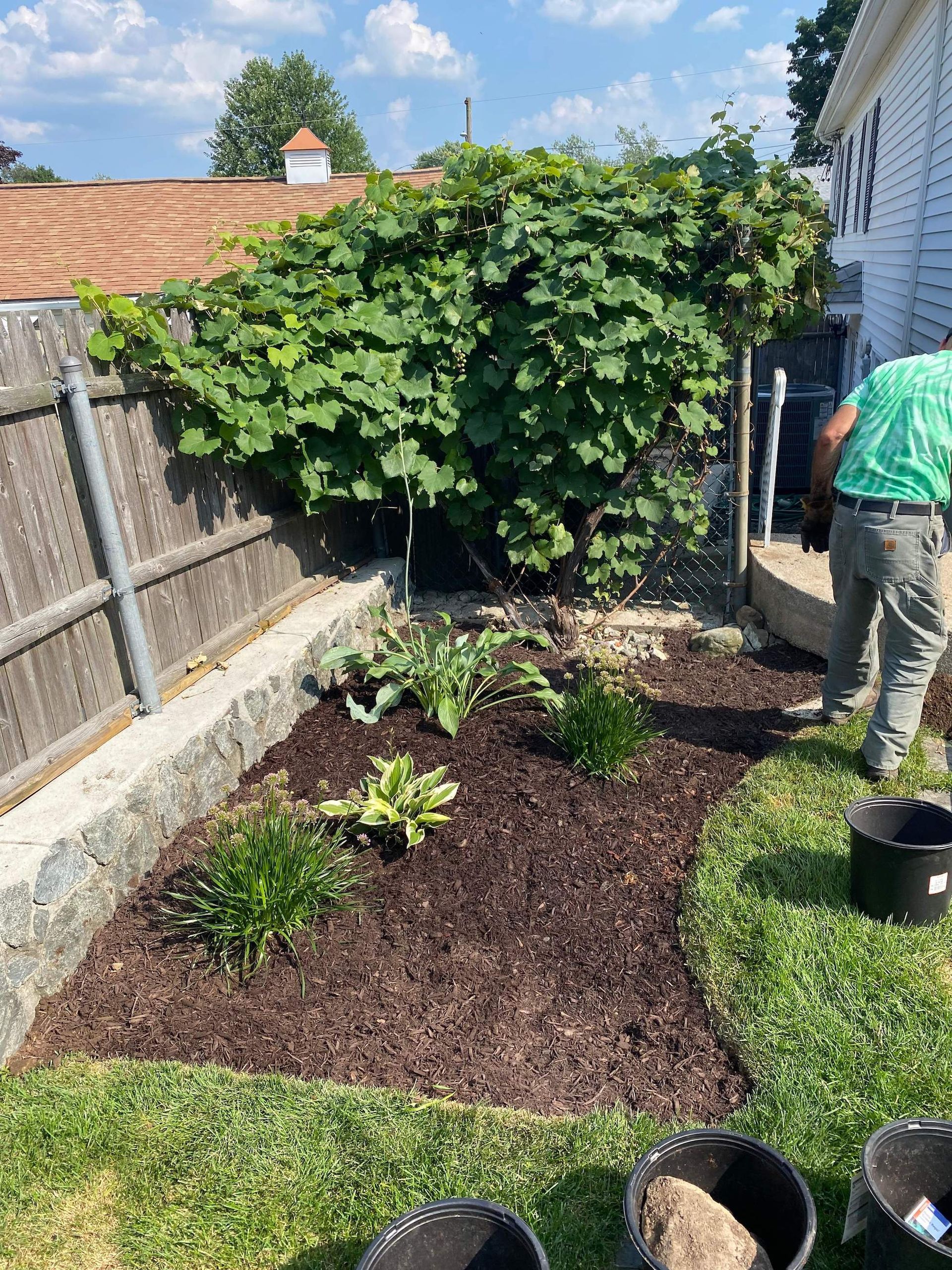 A man is standing in a garden with buckets of mulch.