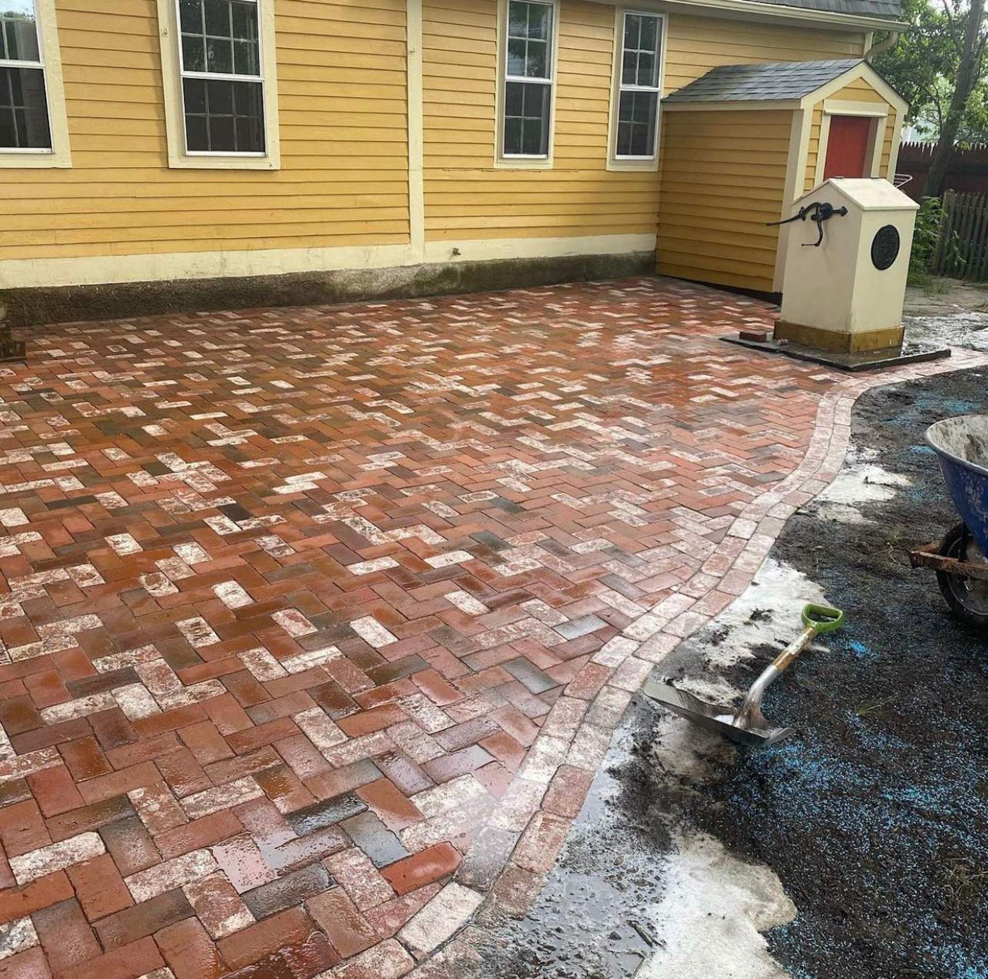 A brick driveway in front of a yellow house