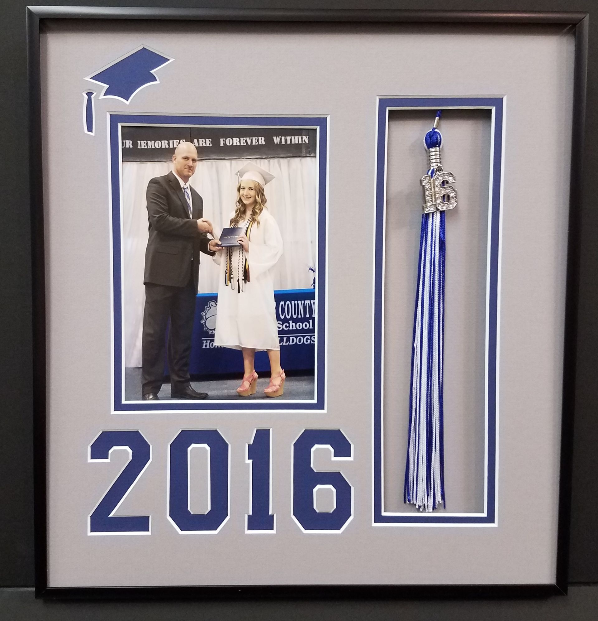 A framed picture of a man giving a woman a diploma in 2016