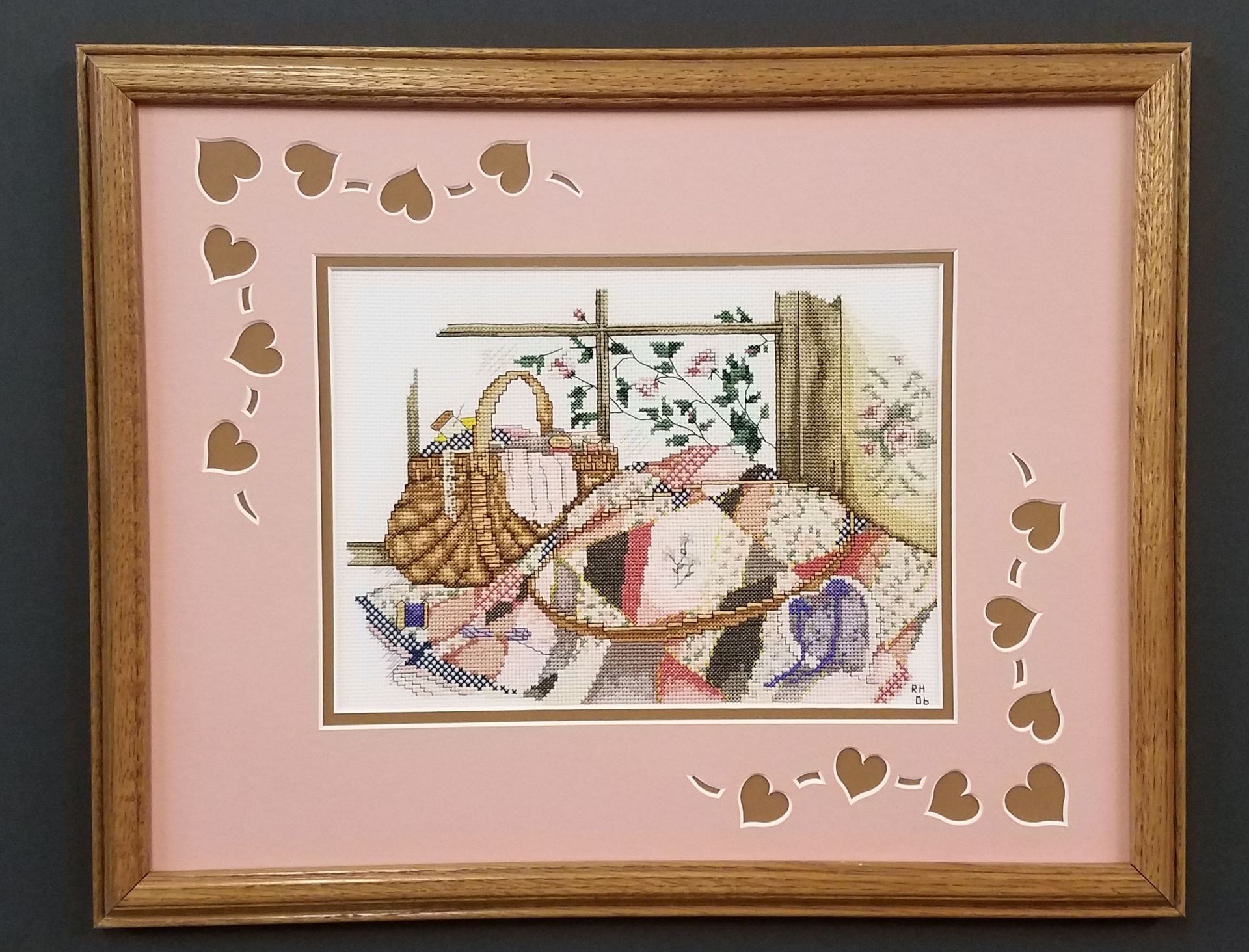 A framed cross stitch picture with hearts around it