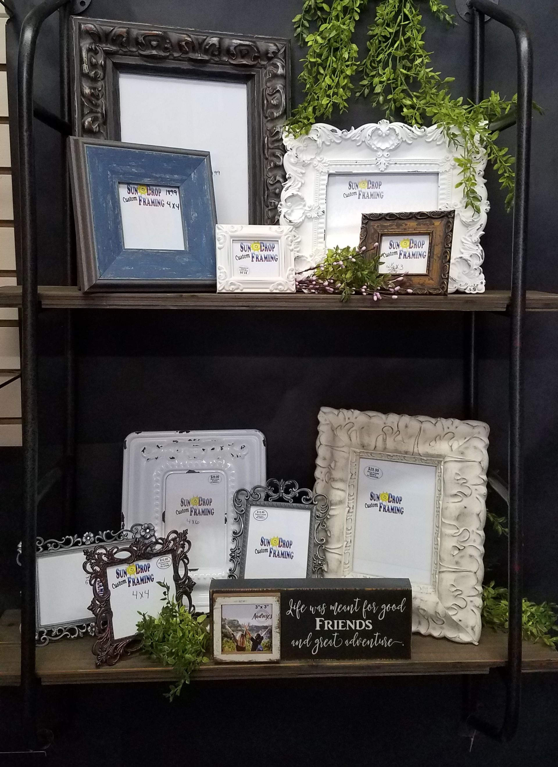 A shelf filled with a variety of picture frames and a sign.
