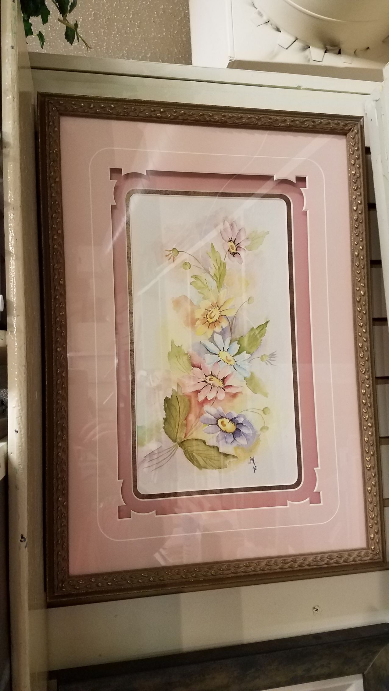 A picture of flowers in a pink frame on a table.