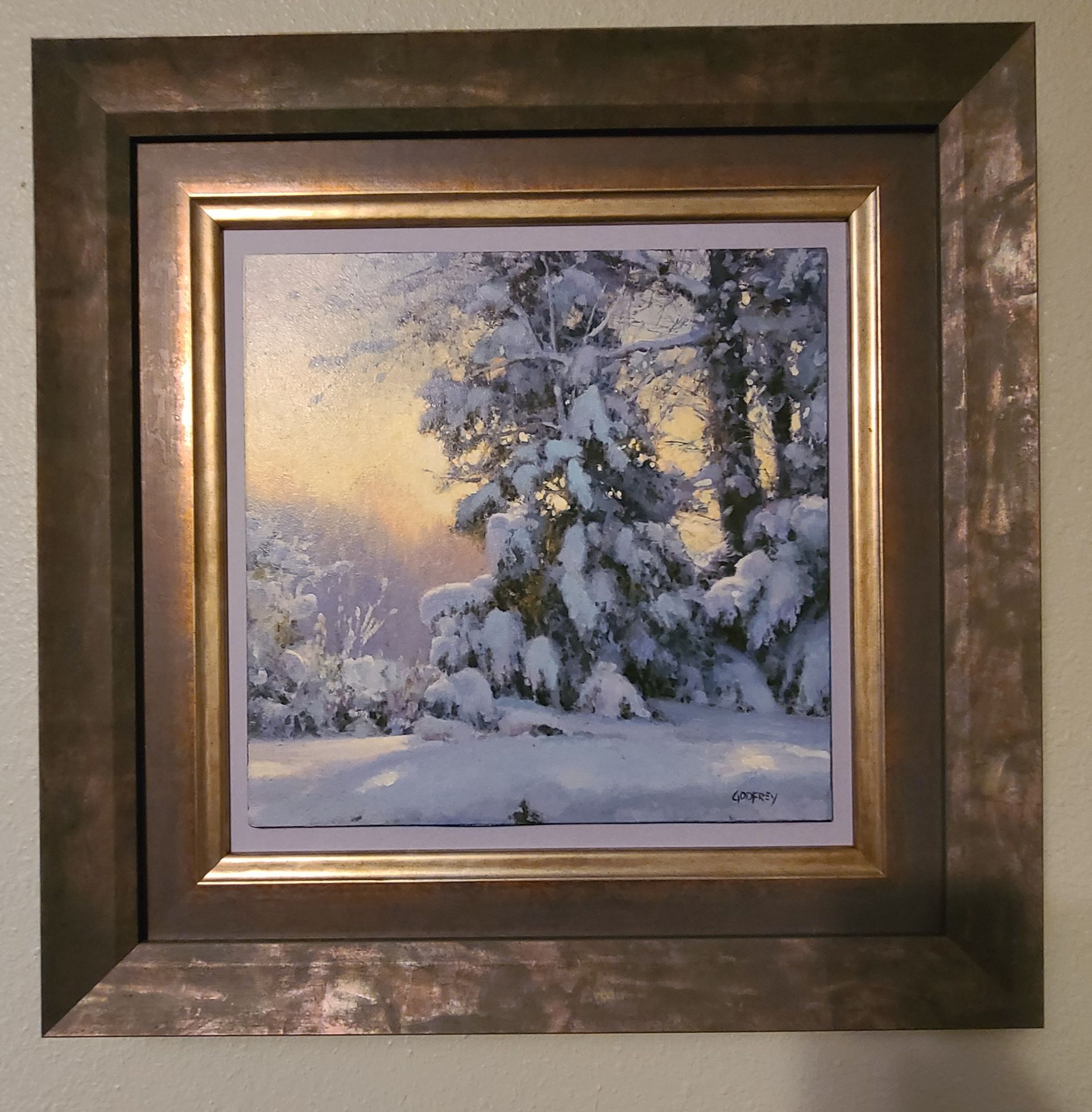 A framed painting of trees covered in snow
