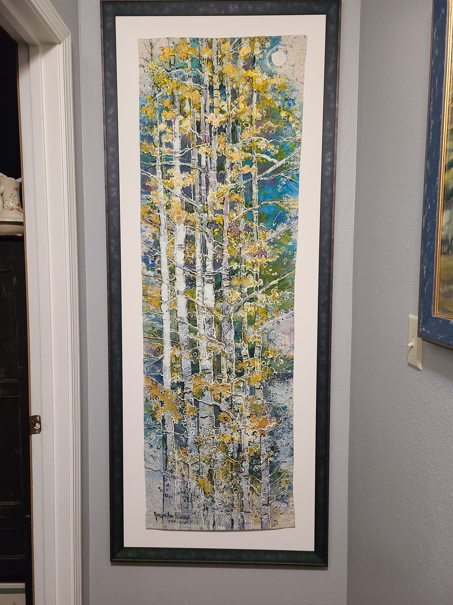 A painting of trees with yellow leaves is hanging on a wall.
