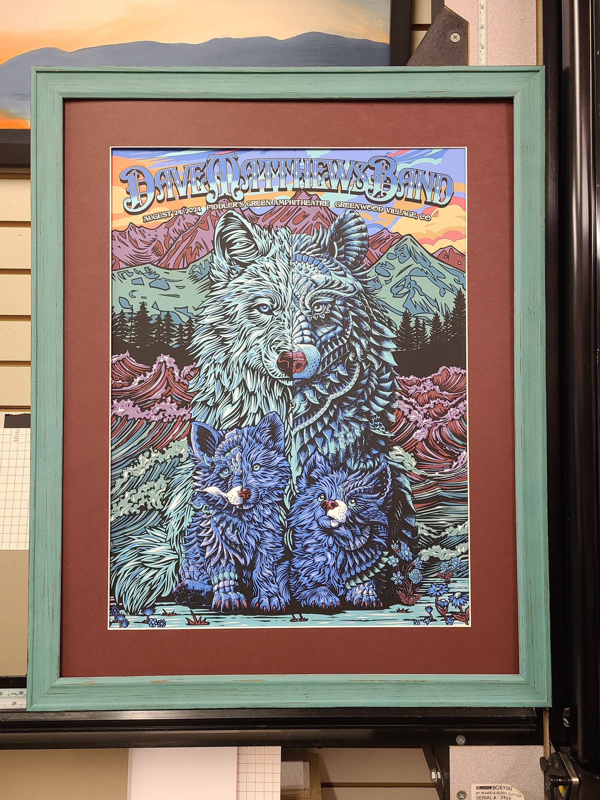 A framed painting of a wolf with mountains in the background