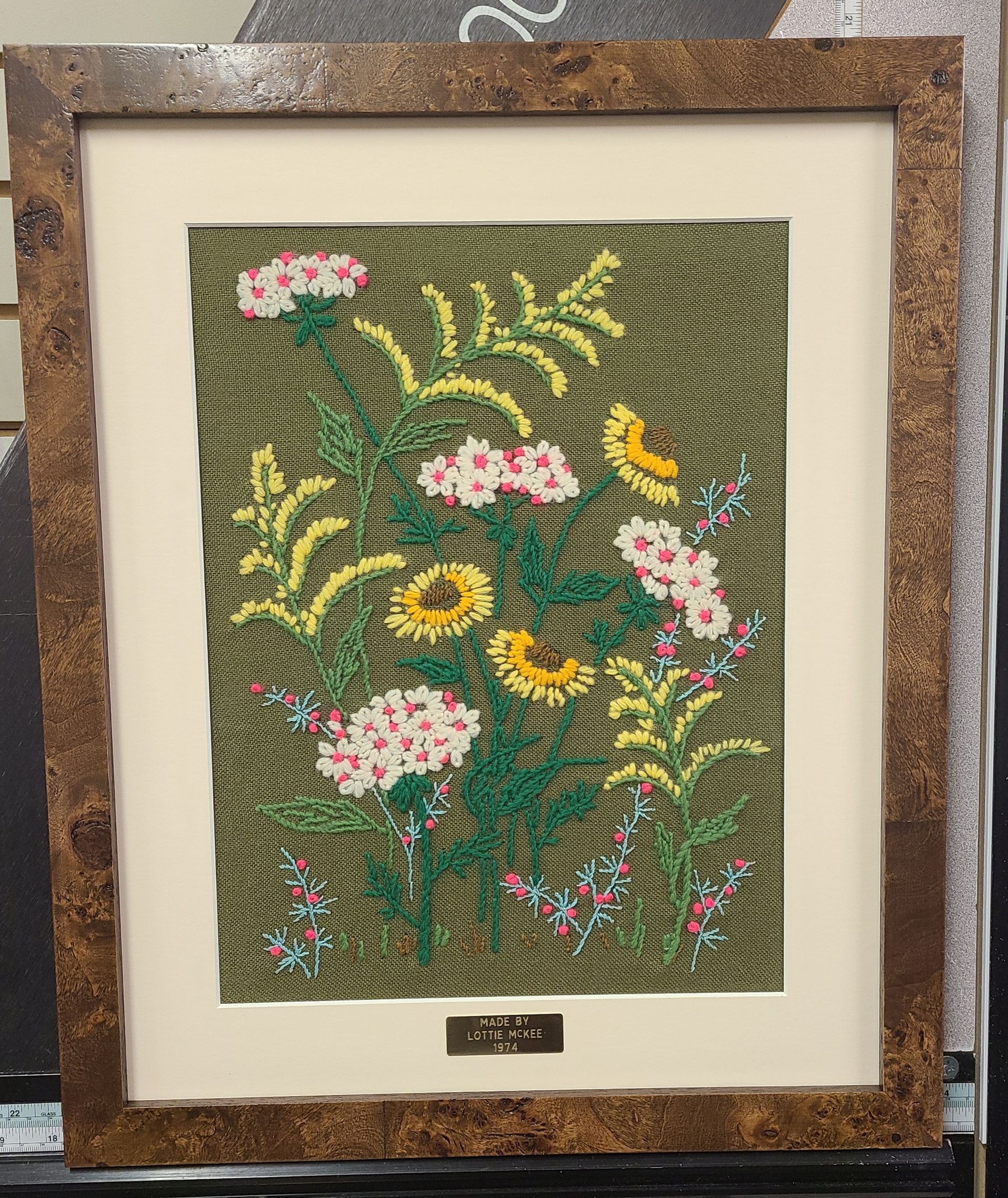 A framed painting of flowers and leaves on a green background
