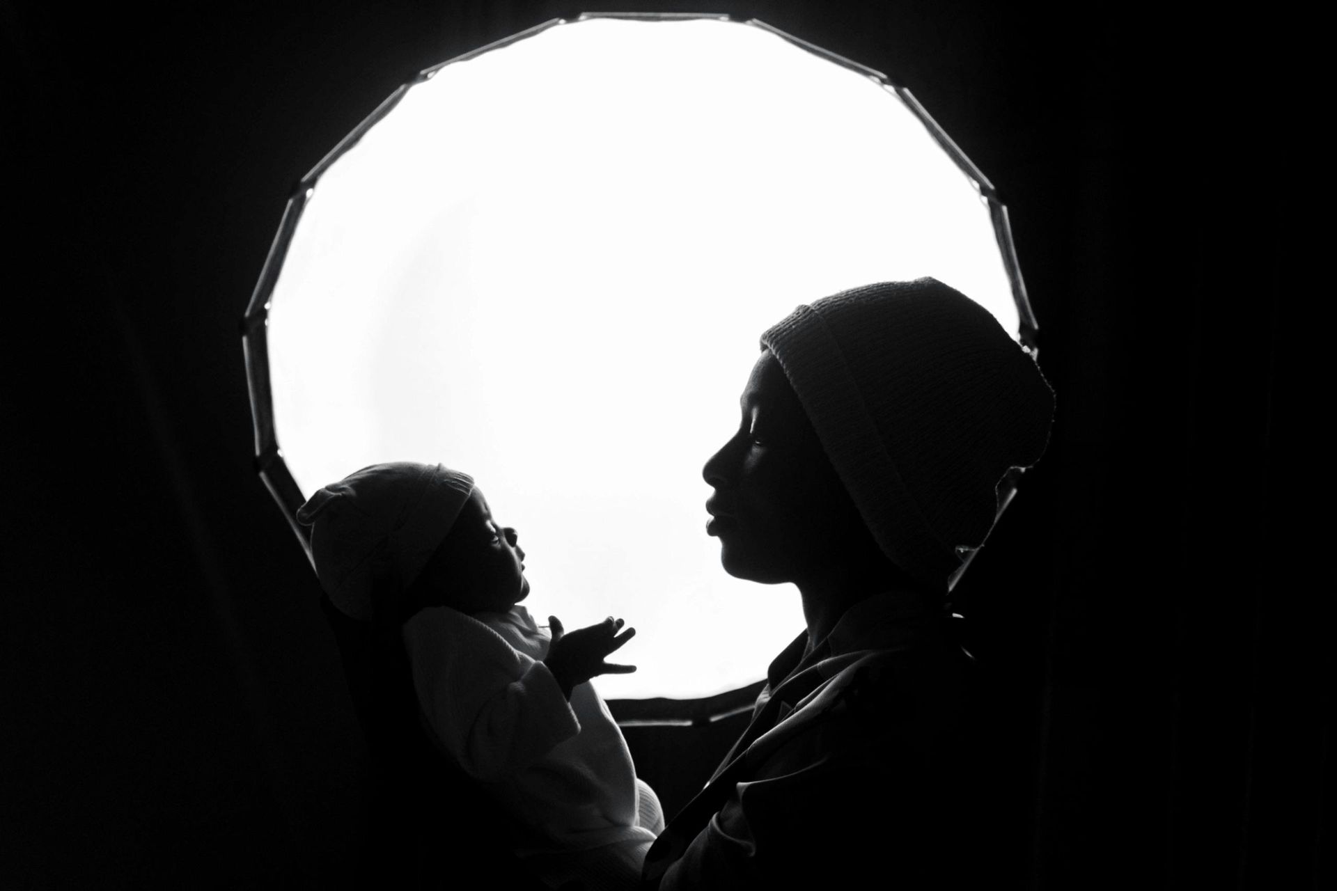A silhouette of a woman holding a baby in front of a window