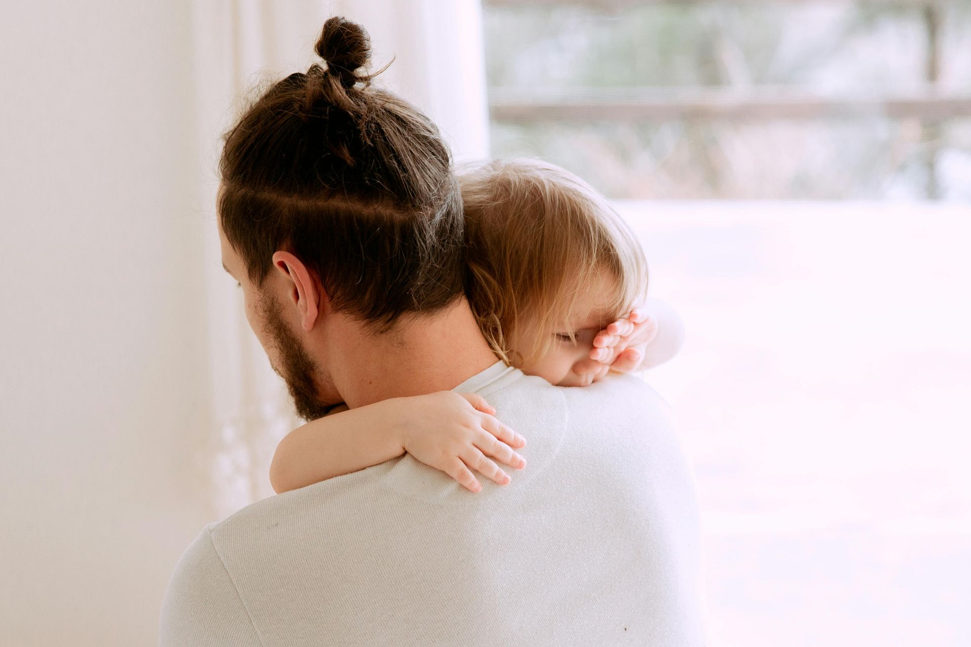 A man is holding a baby on his shoulder.