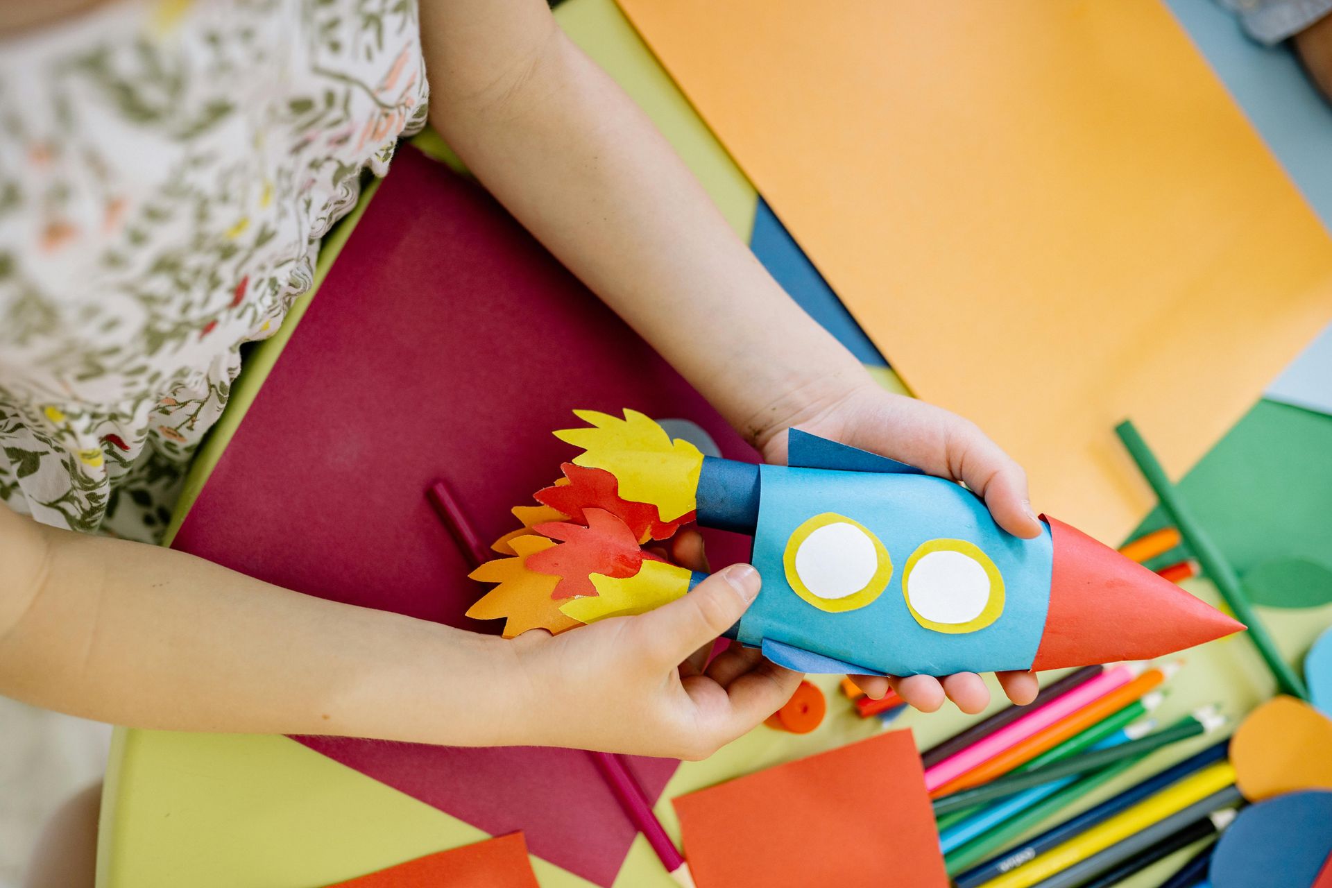 A child is holding a paper rocket in her hands.