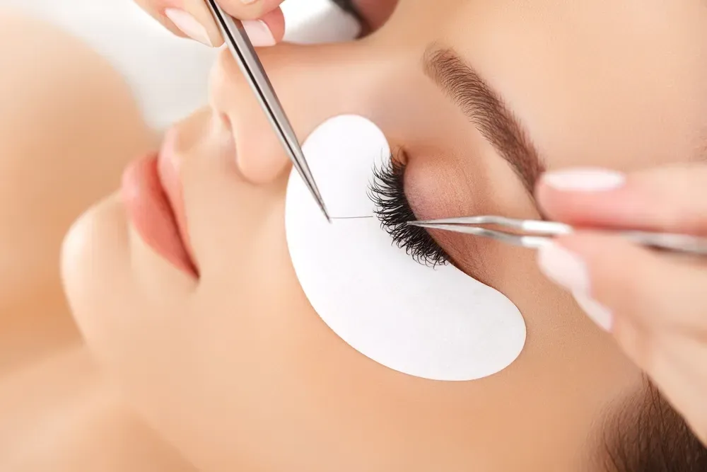 A Woman Having Lashes Applied — Devyani Hair & Beauty in Unanderra, NSW
