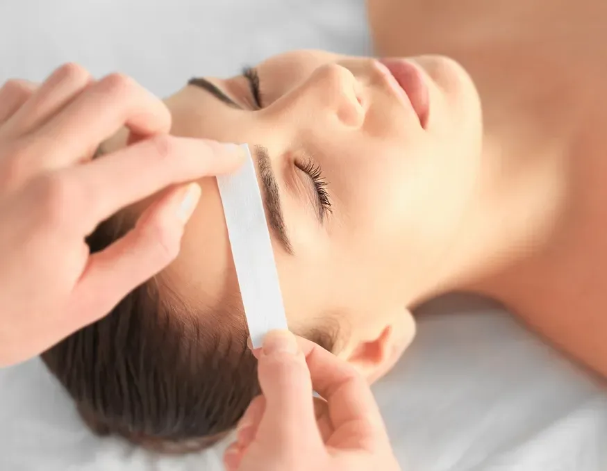 A Beauty Therapist Waxing a Womans Eyebrows — Devyani Hair & Beauty in Unanderra, NSW
