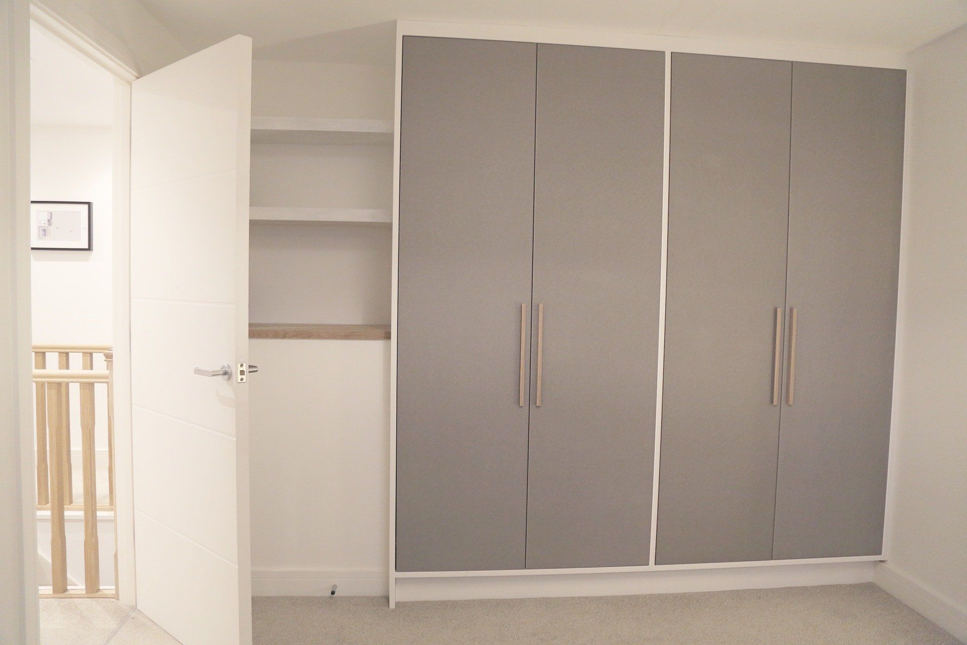 Bespoke valchromat grey wardrobe with oak handles and floating shelves to side of wardrobe.