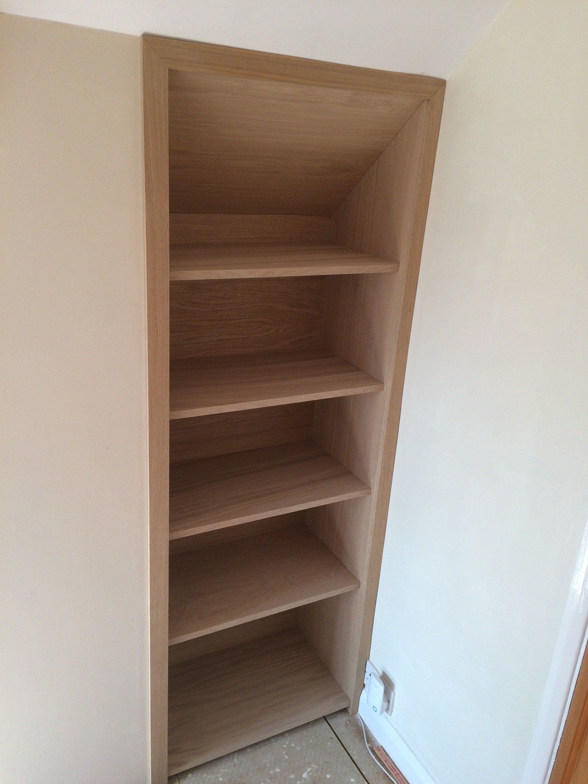 Oak veneer shelving fitted to cubby hole with sloped ceiling.