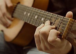 Hands strumming an acoustic guitar
