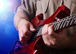 A man playing a red electric guitar