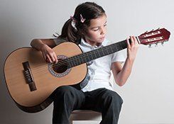 A little girl playing an acoustic guitar