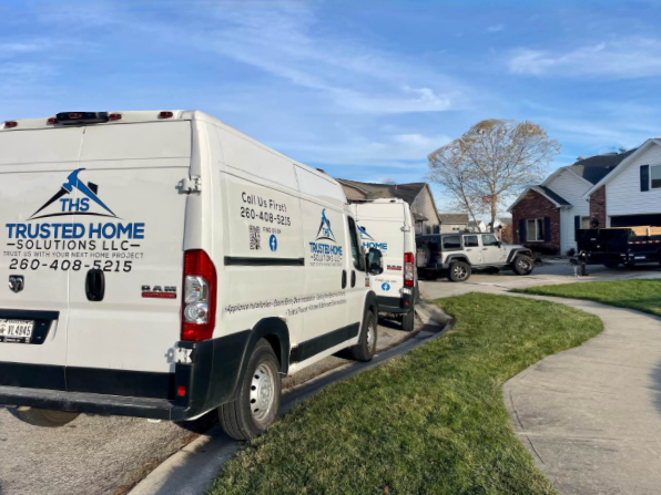 A row of white vans parked in front of a house.