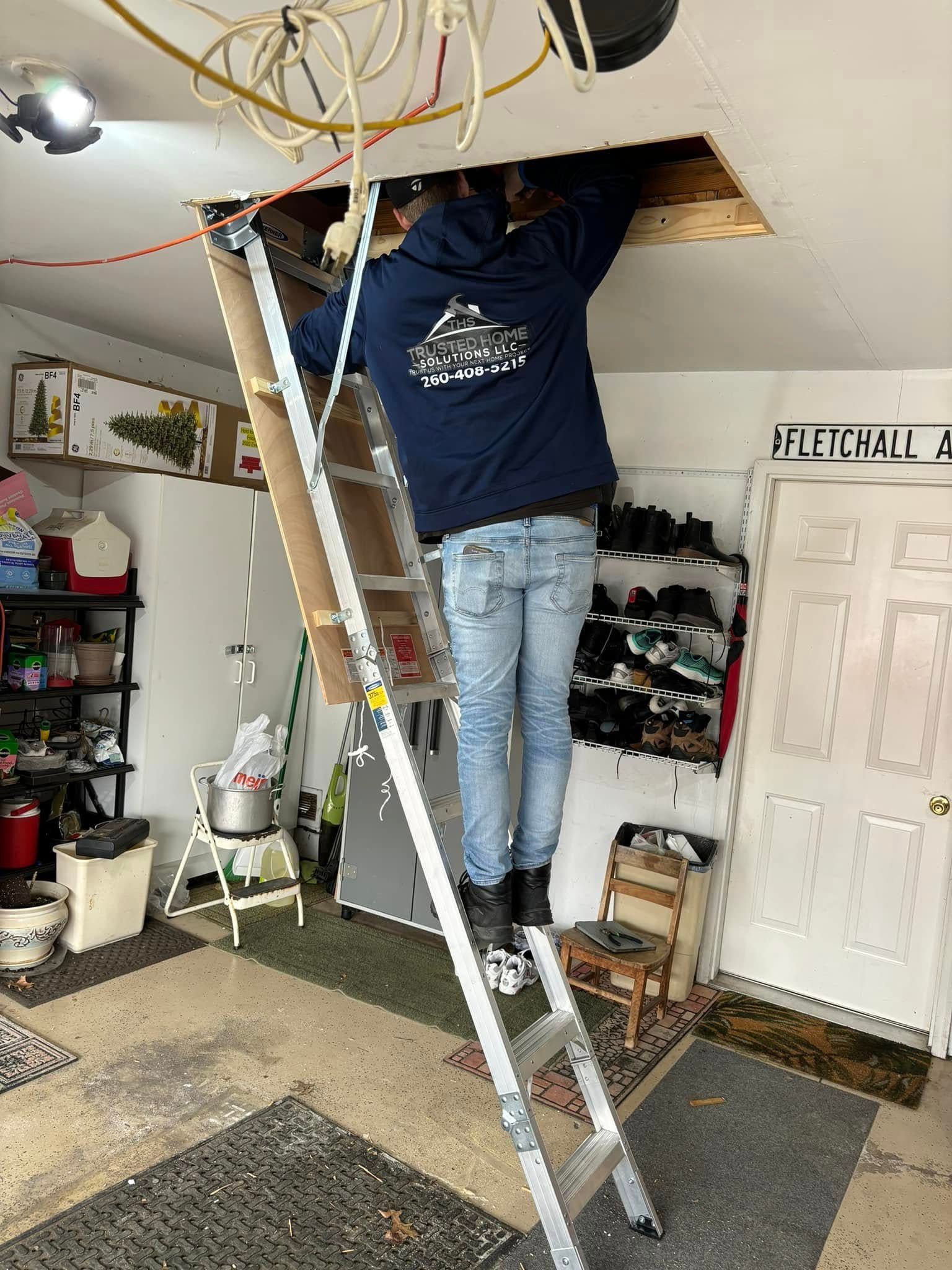 A man is standing on a ladder in a garage.