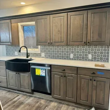 A kitchen with wooden cabinets , stainless steel appliances , a sink , and a window.