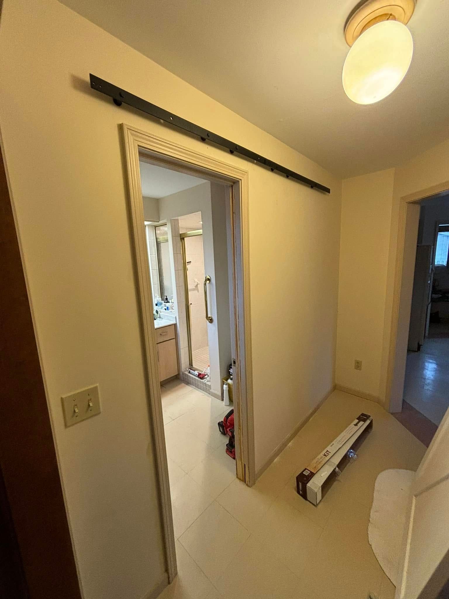 A hallway with a sliding door leading to a bathroom.