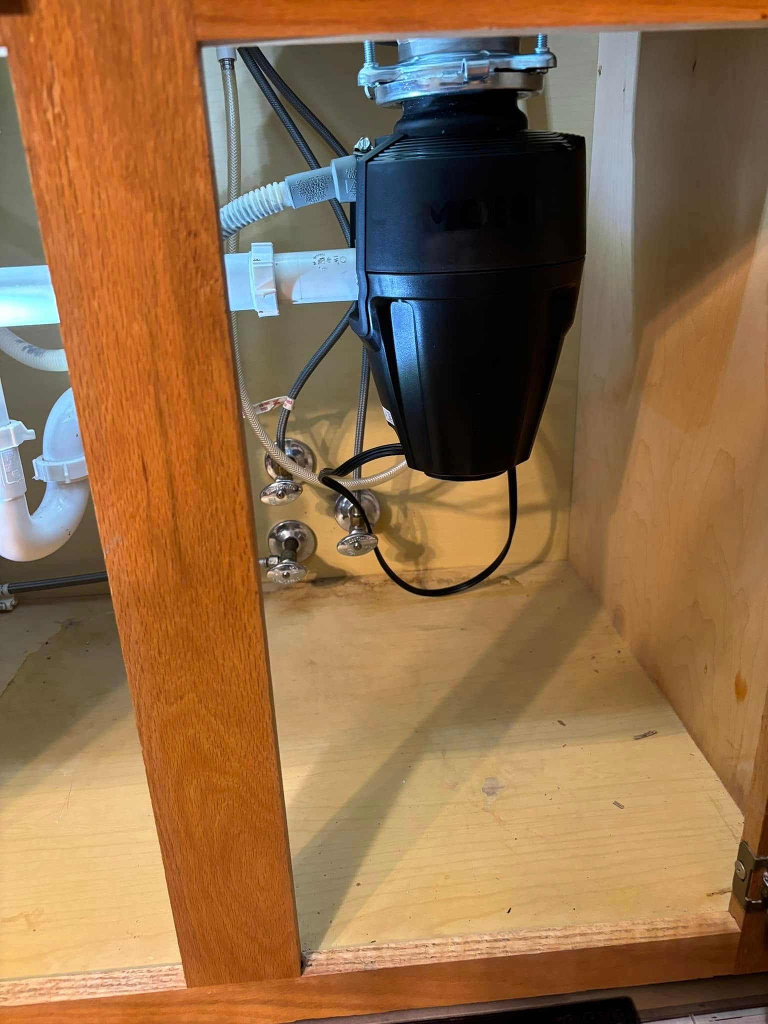 A garbage disposal is sitting under a sink in a cabinet.