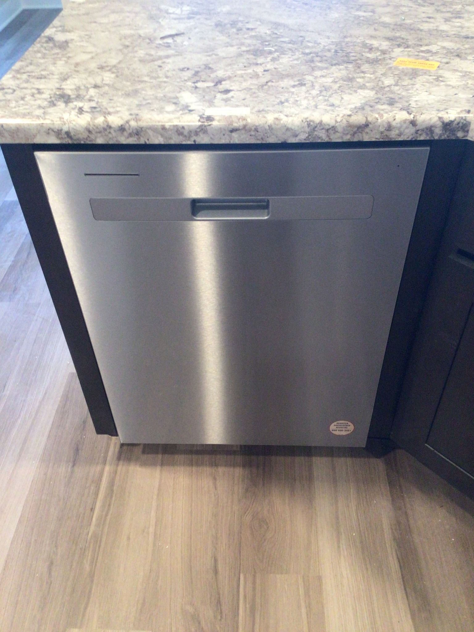 A stainless steel dishwasher is sitting under a granite counter top in a kitchen.