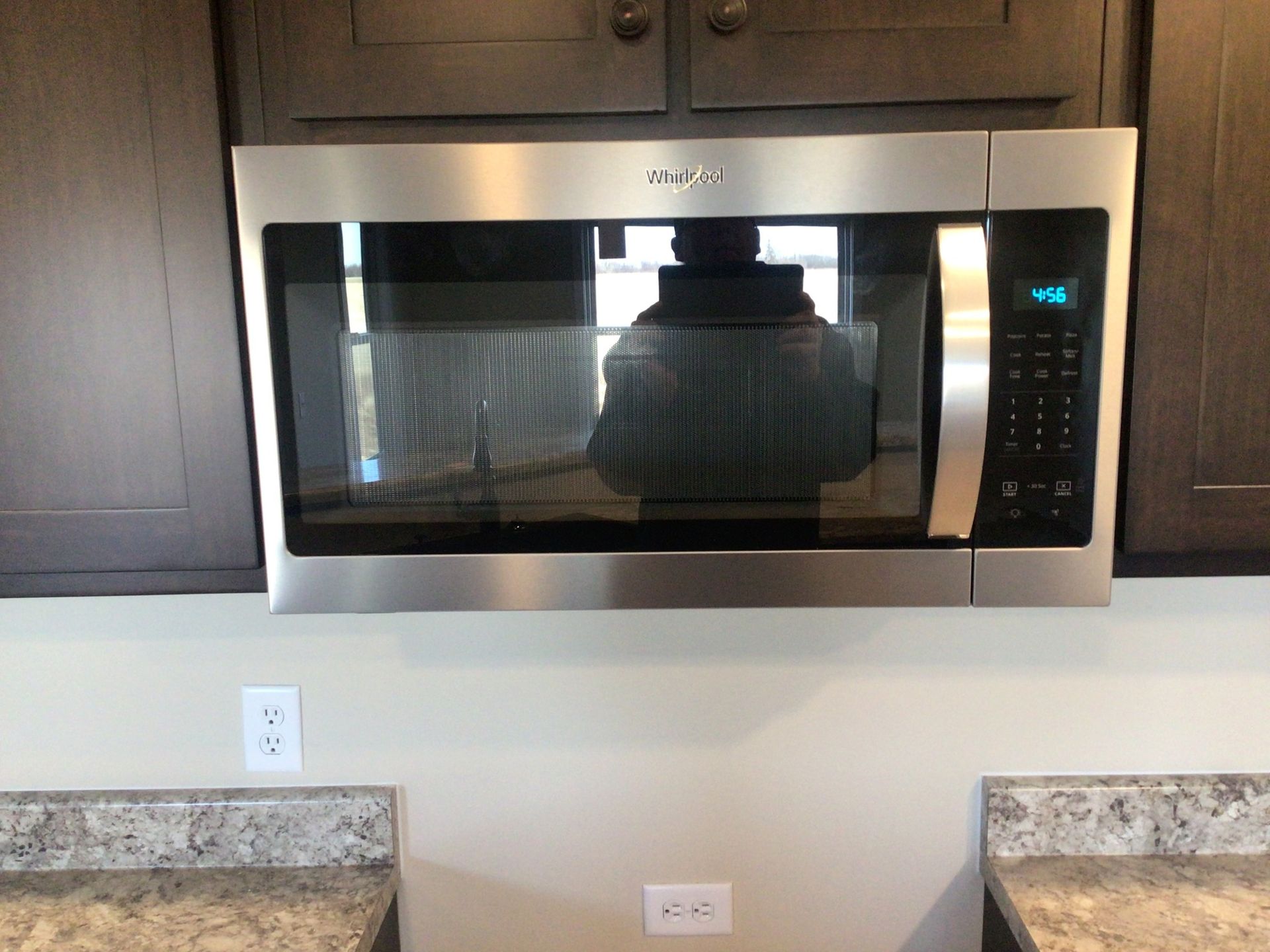 A stainless steel microwave oven is mounted above a counter in a kitchen.