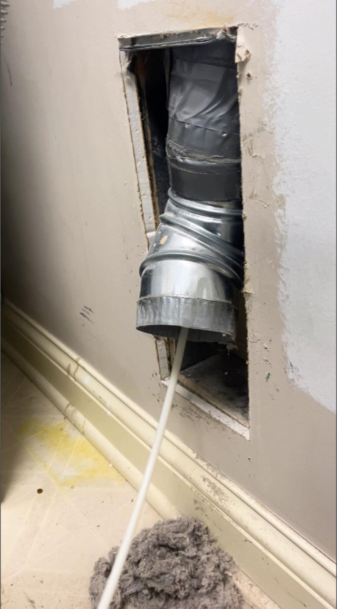 A duct is sticking out of a hole in a wall.