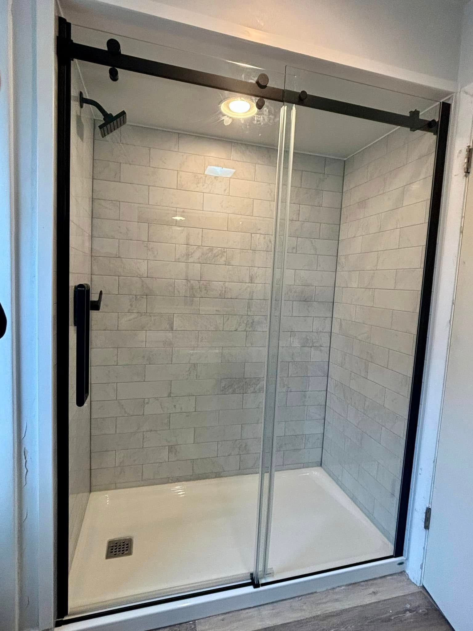 A bathroom with a sliding glass shower door and a shower head.